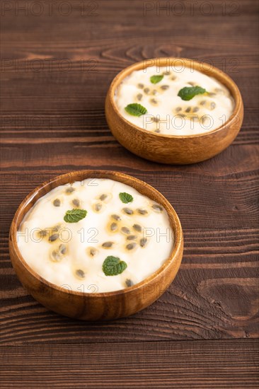 Yoghurt with granadilla and mint in wooden bowl on brown wooden background. side view, close up