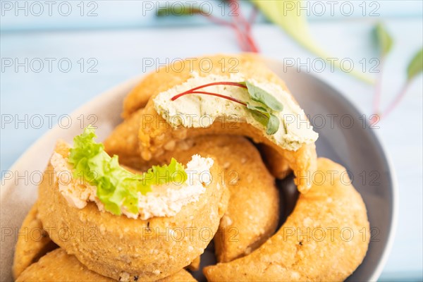 Homemade salted crescent-shaped cheese cookies, cup of coffee on blue wooden background. side view, selective focus