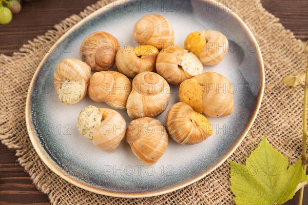 Grape (Burgundy) snails with butter and cheese on brown wooden background and linen textile. Side view, selective focus