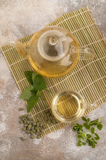 Green oolong tea with herbs in glass on brown concrete background. Healthy drink concept. Top view, flat lay