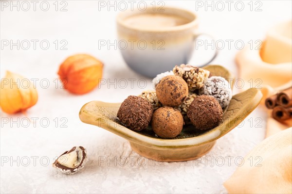 Chocolate truffle candies with cup of coffee on a gray concrete background and orange textile. side view, close up, selective focus