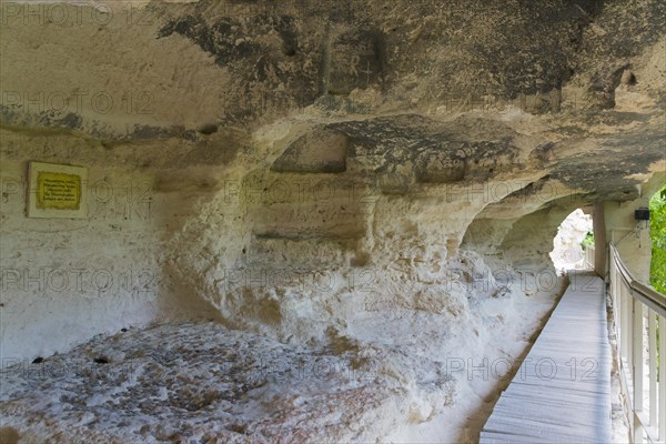 A walkway leads through a cave entrance, accompanied by information signs, cells of the monks, Aladja Monastery, Aladja Monastery, Aladzha Monastery, medieval rock monastery, cave monastery in the limestone cliff, Varna, Black Sea coast, Bulgaria, Europe