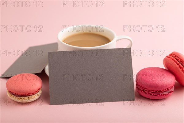 Gray paper business card mockup with red and purple macaroons and cup of coffee on pink pastel background. Blank, side view, copy space, still life, close up. morning, breakfast concept