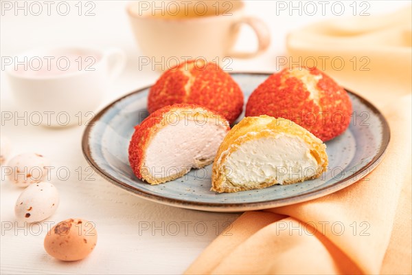 Traditional french custard dessert shu cake and cup of green tea on white wooden background and orange linen textile. side view, close up, selective focus. Breakfast, morning, concept