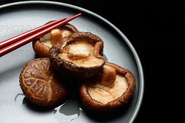 Dried and soaked shiitake mushrooms on a plate with chopsticks