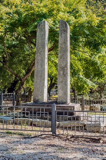 Ancient stone carved flag pole supports in front of lush green trees at Buddhist temple in Gimje-si, South Korea, Asia