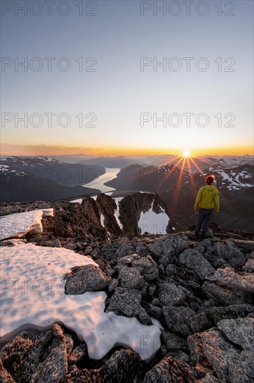 View of mountains and fjord Faleidfjorden, sun star at sunset, mountaineer at the summit of Skala, Loen, Norway, Europe