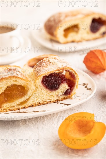 Homemade sweet bun with apricot jam and cup of coffee on gray concrete background. side view, close up, selective focus