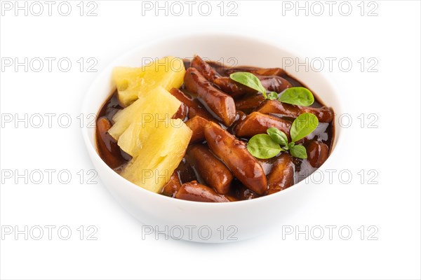 Tteokbokki or Topokki, fried rice cake stick, popular Korean street food with spicy jjajang sauce and pineapple isolated on white background. Side view