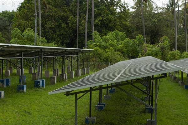 Solar power plant energy panels on tropical island Gili Air, Indonesia. Cloudy day, tropical forest, renewable energy concept