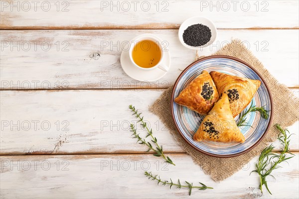 Homemade asian pastry samosa, cup of green tea on white wooden background and linen textile. top view, flat lay, copy space