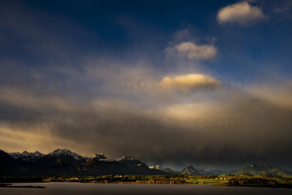 Lake Hopfensee with stormy sky in soft morning light and Allgaeu mountains in the background, Hopfen am See, Ostallgaeu, Swabia, Bavaria, Germany, Europe