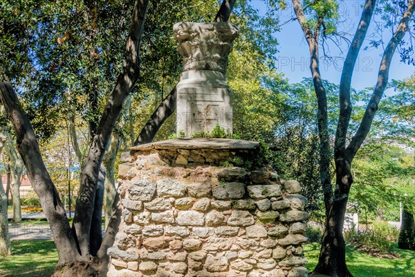 Base and capstone of roman column on top of section of stone wall in park in Istanbul, Tuerkiye