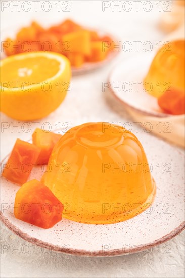 Papaya and orange jelly on gray concrete background and orange linen textile. side view, flat lay, close up, selective focus
