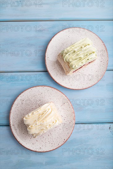 Roll biscuit cake with cream cheese and jam on blue wooden background, top view, flat lay, close up