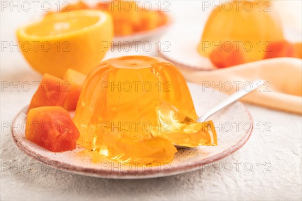 Papaya and orange jelly on gray concrete background and orange linen textile. side view, flat lay, close up, selective focus