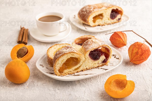 Homemade sweet bun with apricot jam and cup of coffee on gray concrete background. side view, close up