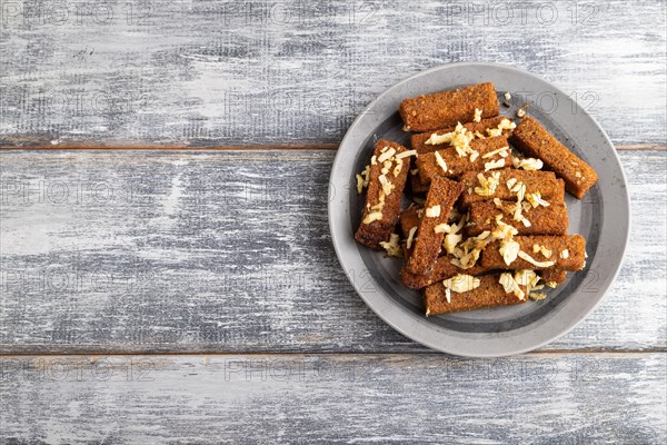 Cheese and toast on a gray plate on a gray wooden background. Top view, flat lay, close up, copy space