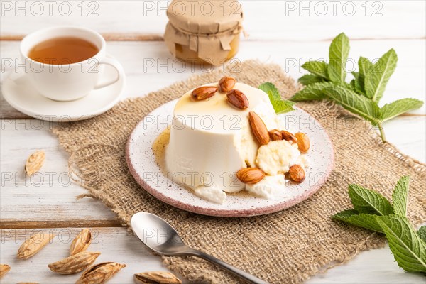 Ricotta cheese with honey and almonds on white wooden background and linen textile. side view, close up