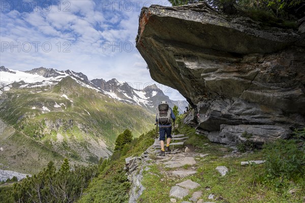 Mountaineer on a hiking trail under a rocky outcrop in a picturesque mountain landscape, Berliner Hoehenweg, Zillertal Alps, Tyrol, Austria, Europe