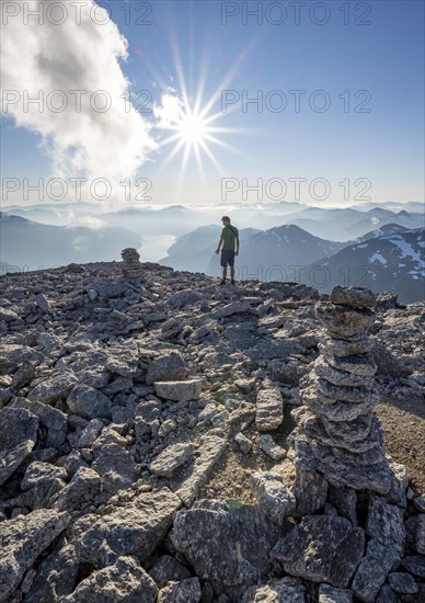 Mountaineer on the summit of Skala with cairn, view of mountain landscape and fjord Faleidfjorden, Sonnenstern, Loen, Norway, Europe