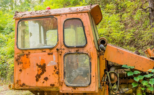 Left side cab section of old, rusting, broken down bulldozer abandoned in wilderness