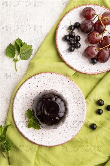 Black currant and grapes jelly on gray concrete background and green linen textile. top view, flat lay, close up