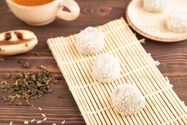 Japanese rice sweet buns mochi filled with pandan and coconut jam and cup of green tea on brown wooden background. side view, close up, selective focus