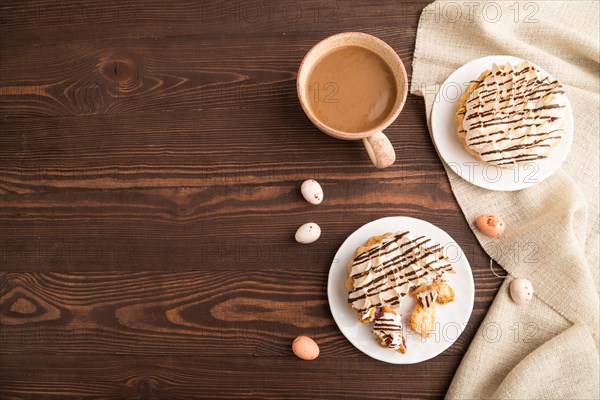 Tartlets with meringue cream and cup of coffee on brown wooden background and linen textile. top view, flat lay, copy space. Breakfast, morning, concept