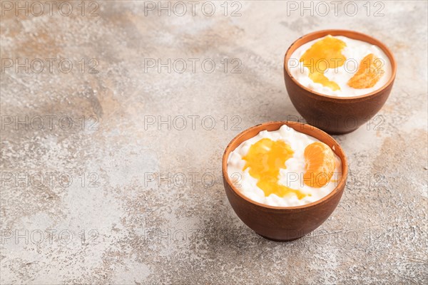 Grained cottage cheese with tangerine jam on brown concrete background. side view, copy space