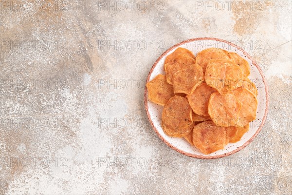 Slices of dehydrated salted meat chips with herbs and spices on gray concrete background. Top view, flat lay, copy space