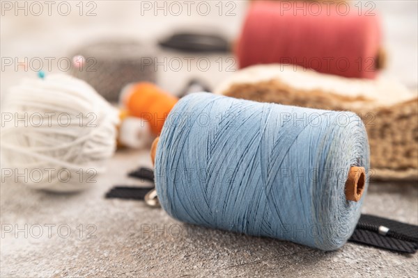 Sewing accessories: scissors, thread, thimbles, braid on brown concrete background. Side view, close up, selective focus