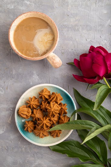 Homemade soft caramel fudge candies on blue plate and cup of coffee on gray concrete background, peony flower decoration. top view, flat lay, close up
