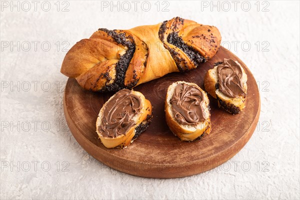 Homemade sweet bun with chocolate cream on a gray concrete background. side view, close up