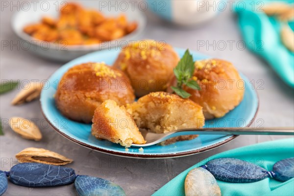 Homemade traditional turkish dessert sekerpare with almonds and honey, cup of green tea on gray concrete background and blue textile. side view, selective focus