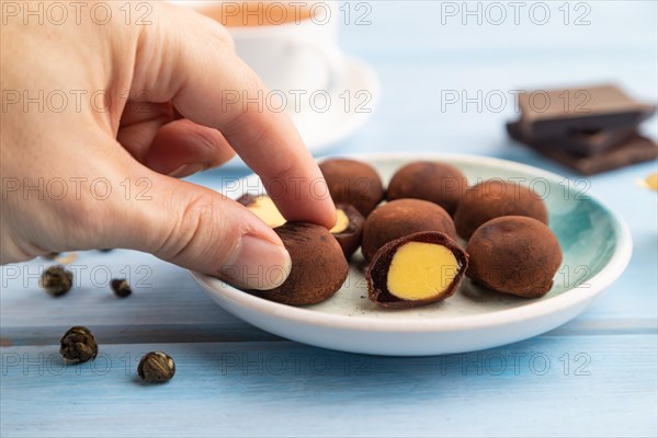 Japanese rice sweet buns chocolate mochi filled with cream and cup of green tea with hand on blue wooden background. side view, close up, selective focus