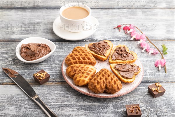 Homemade waffle with chocolate butter and cup of coffee on a gray wooden background. side view, close up