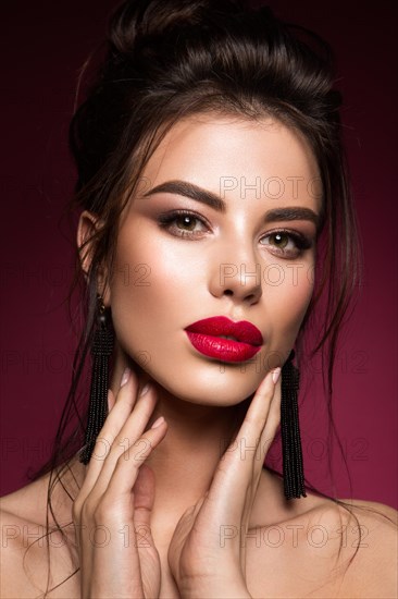 Gorgeous Young Brunette Woman face portrait. Beauty Model Girl with bright eyebrows, perfect make-up, red lips, touching her face. Sexy lady makeup for party
