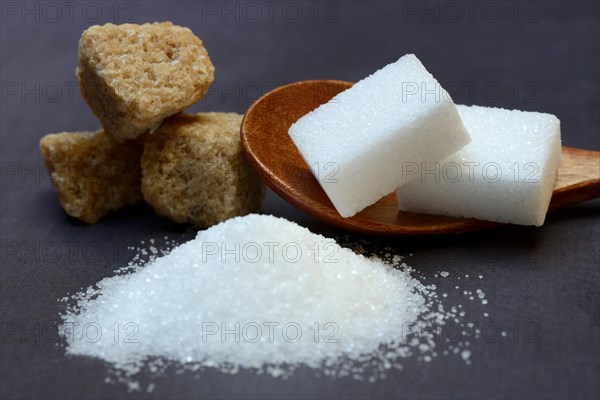 Granulated sugar and sugar cubes in spoons, brown raw sugar