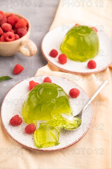 Mint and raspberry green jelly on gray concrete background and orange linen textile. side view, close up, selective focus