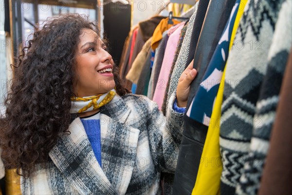 Close-up portrait of a smiling woman looking clothes in a vintage second hand store