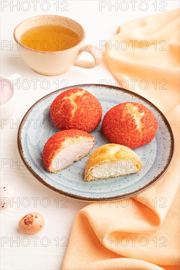 Traditional french custard dessert shu cake and cup of green tea on white wooden background and orange linen textile. side view, close up. Breakfast, morning, concept
