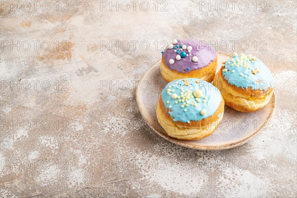 Purple and blue glazed donut on brown concrete background. side view, copy space. Breakfast, morning, concept