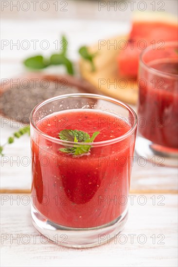 Watermelon juice with chia seeds and mint in glass on a white wooden background with linen textile. Healthy drink concept. Side view, close up, selective focus