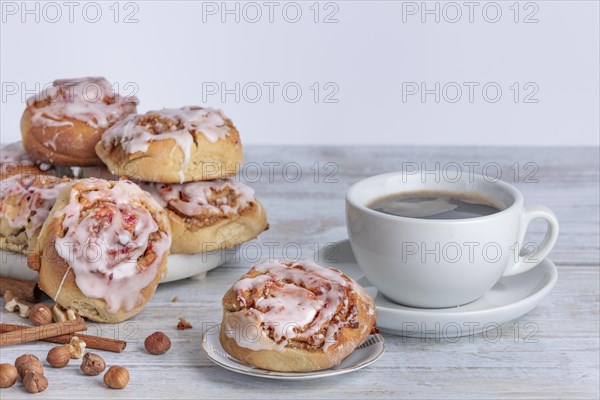 Homemade cinnamon buns next to cup with coffee, copy space, white background