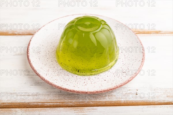 Mint green jelly on white wooden background. side view, close up