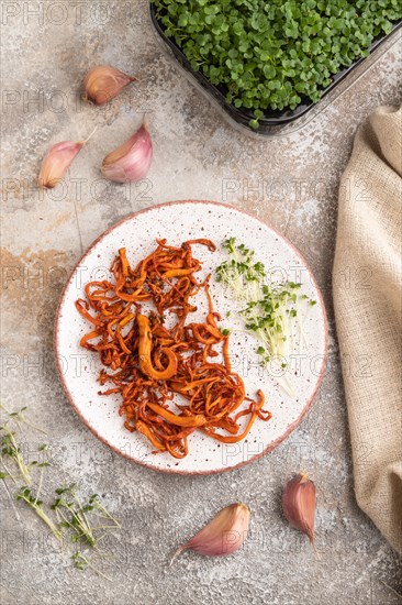 Fried Cordyceps militaris mushrooms on brown concrete background with microgreen, herbs and spices. Top view, flat lay, close up