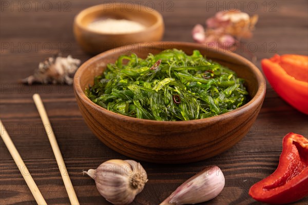 Chuka seaweed salad in wooden bowl on brown wooden background. Side view, close up, selective focus