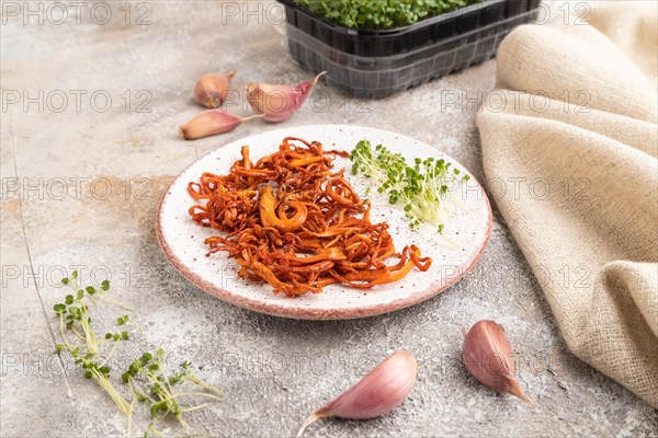 Fried Cordyceps militaris mushrooms on brown concrete background with microgreen, herbs and spices. Side view, copy space