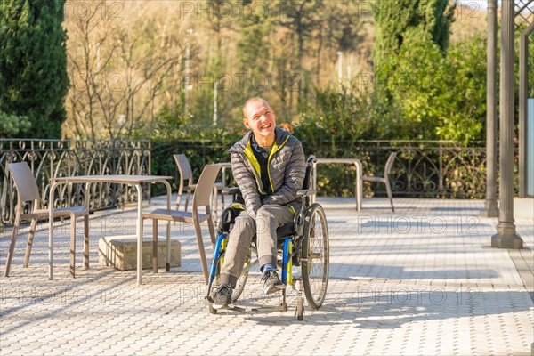 Horizontal photo with wide view and copy space of a disabled man in wheelchair enjoying the sun in the park